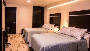 Een hotelkamer met twee bedden, een bureau en een stoel.
