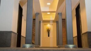 Een moderne hotelentree met een centrale trap, zuilen en inbouwverlichting.