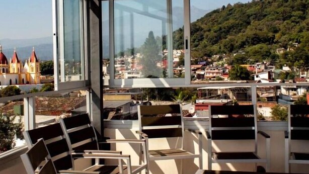 Een balkon met stoelen en uitzicht op een stad met gebouwen en een berg in de verte.
