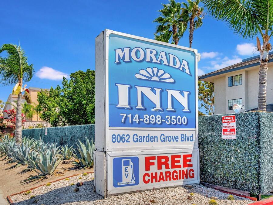 Señal de Morada Inn con un número de teléfono, dirección y comodidades como carga gratuita.