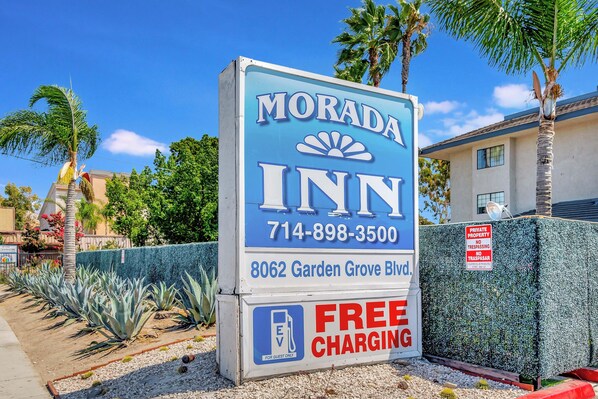 Señal de Morada Inn con un número de teléfono, dirección y comodidades como carga gratuita.