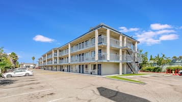 Un motel a più piani con parcheggio, un idrante e una palma.