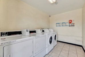 Un área de lavandería con lavadora y secadora de carga frontal, un panel de control y un letrero en la pared.