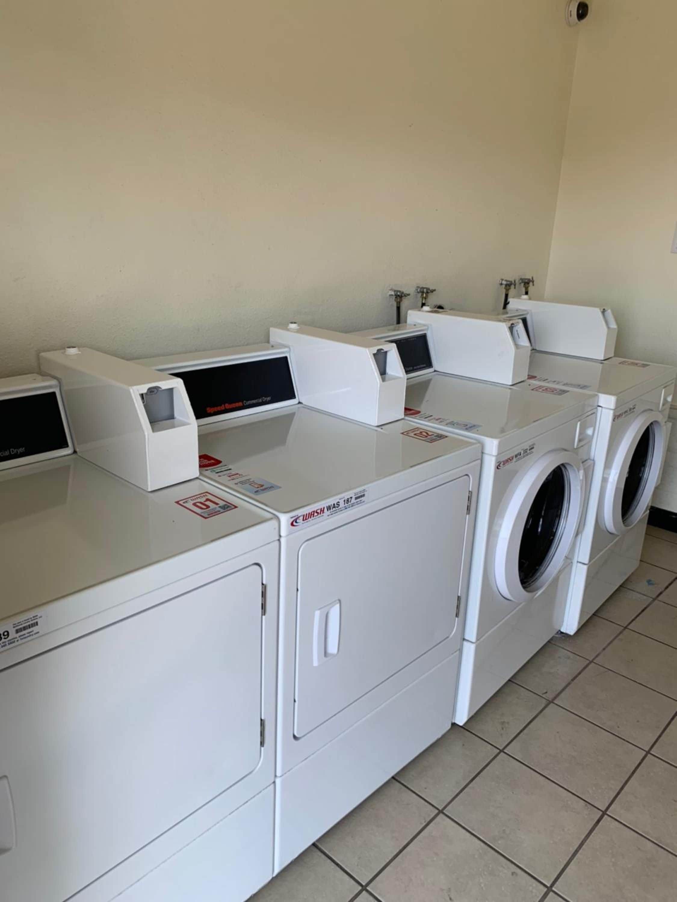 A laundry facility with multiple washing machines and dryers, including a front-loading washer and a top-loading dryer.