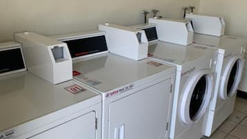 A laundry facility with multiple washing machines and dryers, including a front-loading washer and a top-loading dryer.