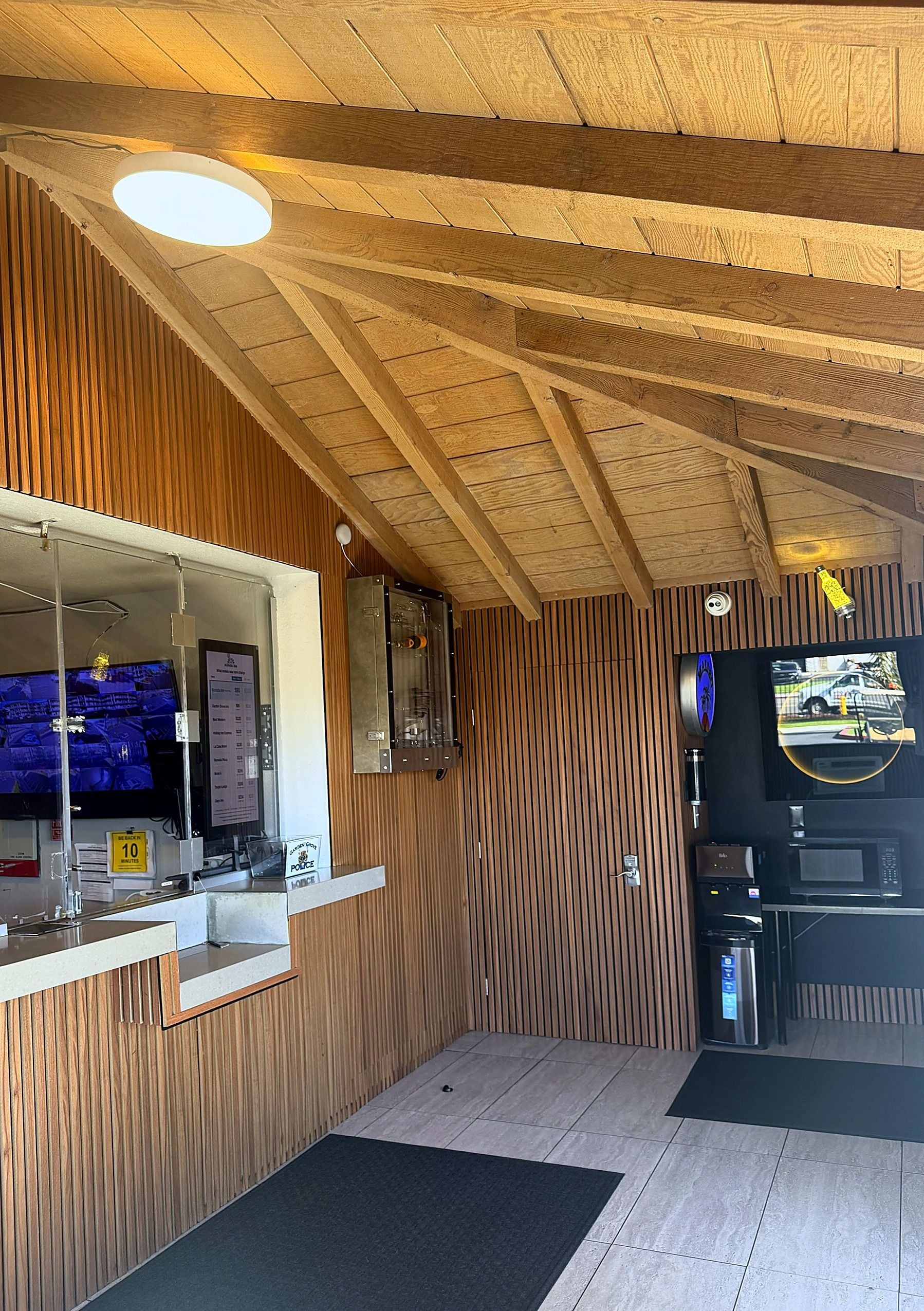 A reception area with a wooden panel wall, a counter, a television, and a surveillance camera.