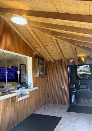 A reception area with a wooden panel wall, a counter, a television, and a surveillance camera. - Morada Inn - Near Garden Grove Park (Garden Grove)