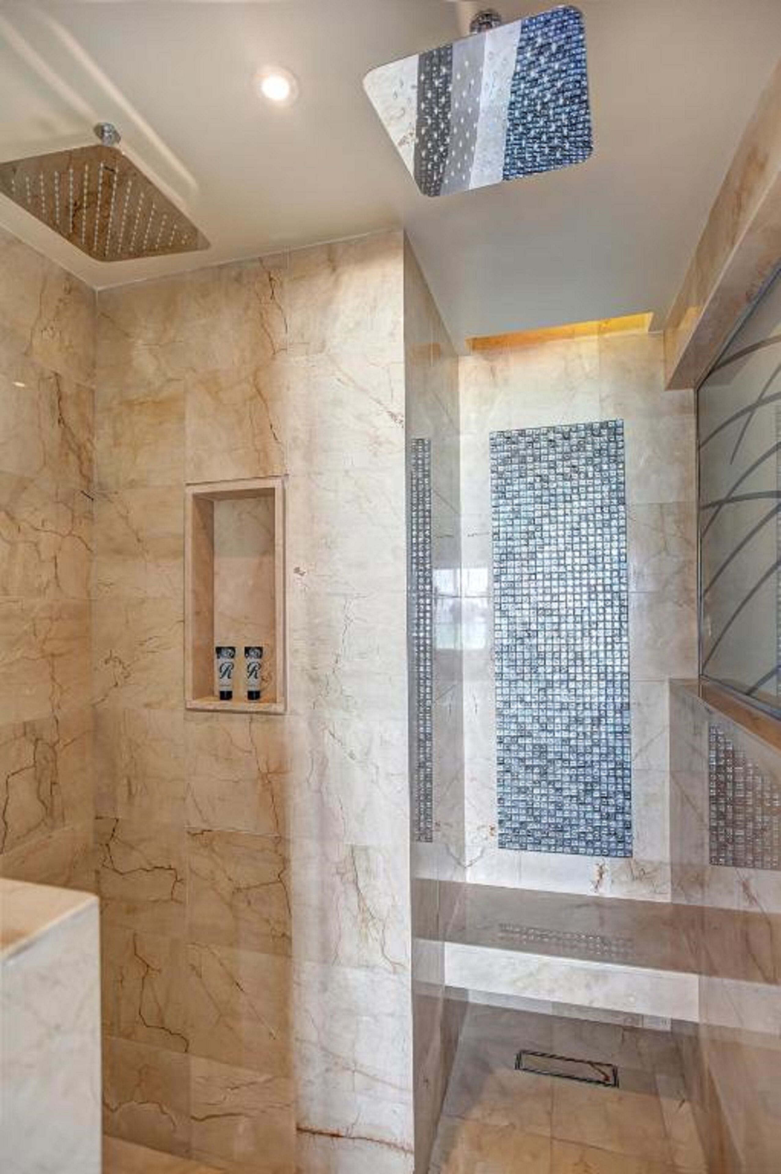 A bathroom with a shower, marble walls, and a tiled shower area.