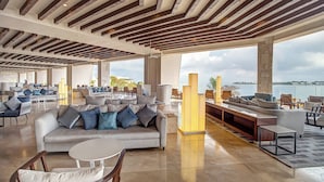 A spacious lounge area with a large sofa, multiple seating options, and a view of the water. - Royalton Negril, An Autograph Collection All-Inclusive Resort (Negril)