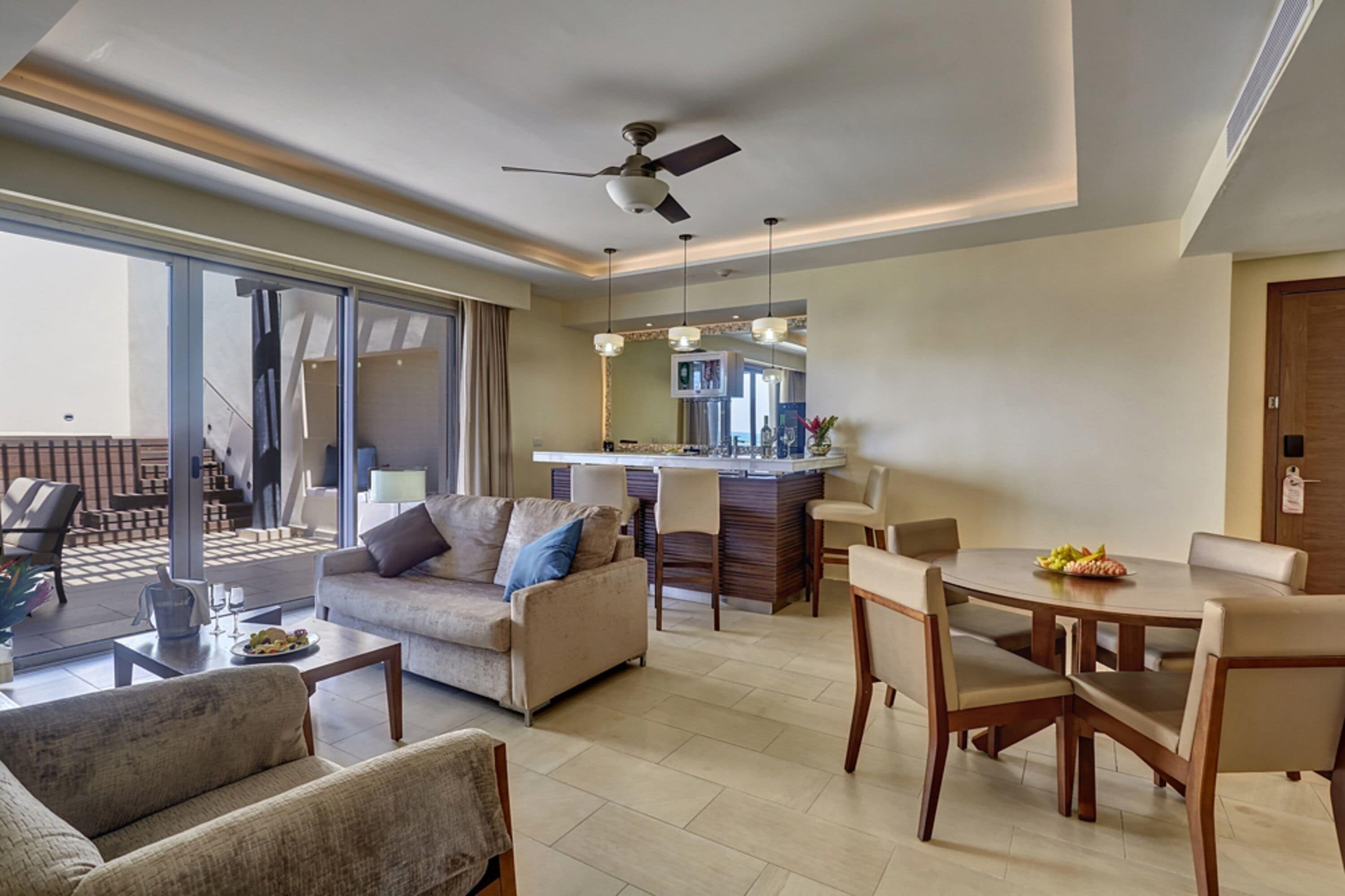 A modern living room with a sofa, chairs, a dining table, and a kitchen area with a bar.