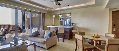 A modern living room with a sofa, chairs, a dining table, and a kitchen area with a bar.