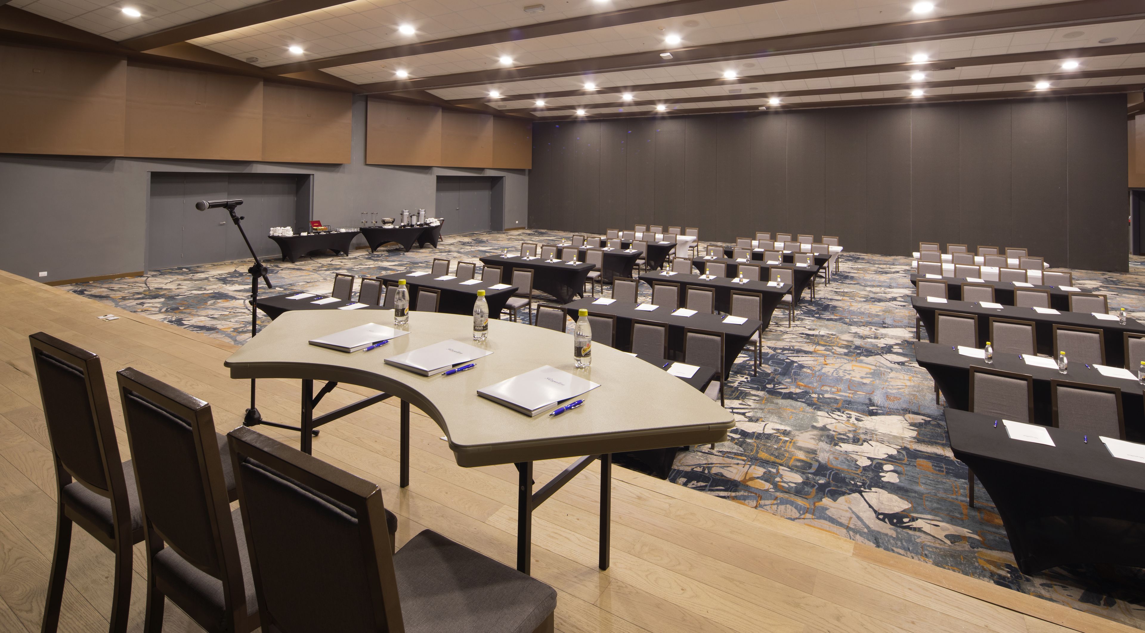 A conference room with multiple tables and chairs, equipped with laptops, water bottles, and nameplates.