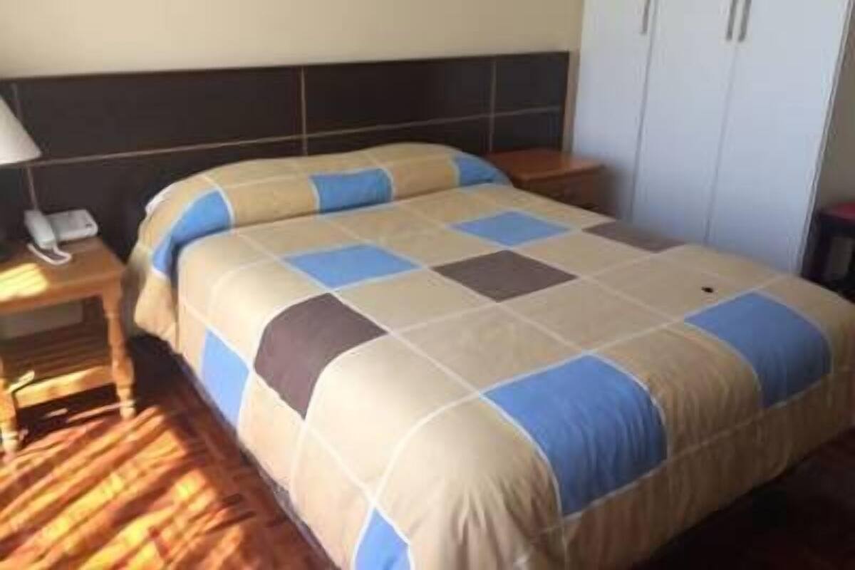 Ein Hotelzimmer mit Bett, Nachttisch, Kleiderschrank und Lampe.