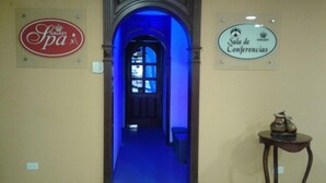 Un pasillo con un arco iluminado en azul que conduce a una sala de conferencias, un cartel de spa y un letrero para la Sala de Conferencias.