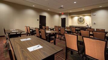 Une salle de conférence dotée de plusieurs tables et chaises, ainsi que de porte-noms et de stylos.