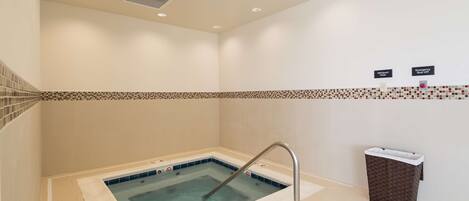 Un área de spa con un jacuzzi, un perchero y un cubo de basura.