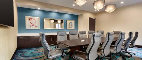 A conference room with a large table, multiple chairs, and a carpeted floor.