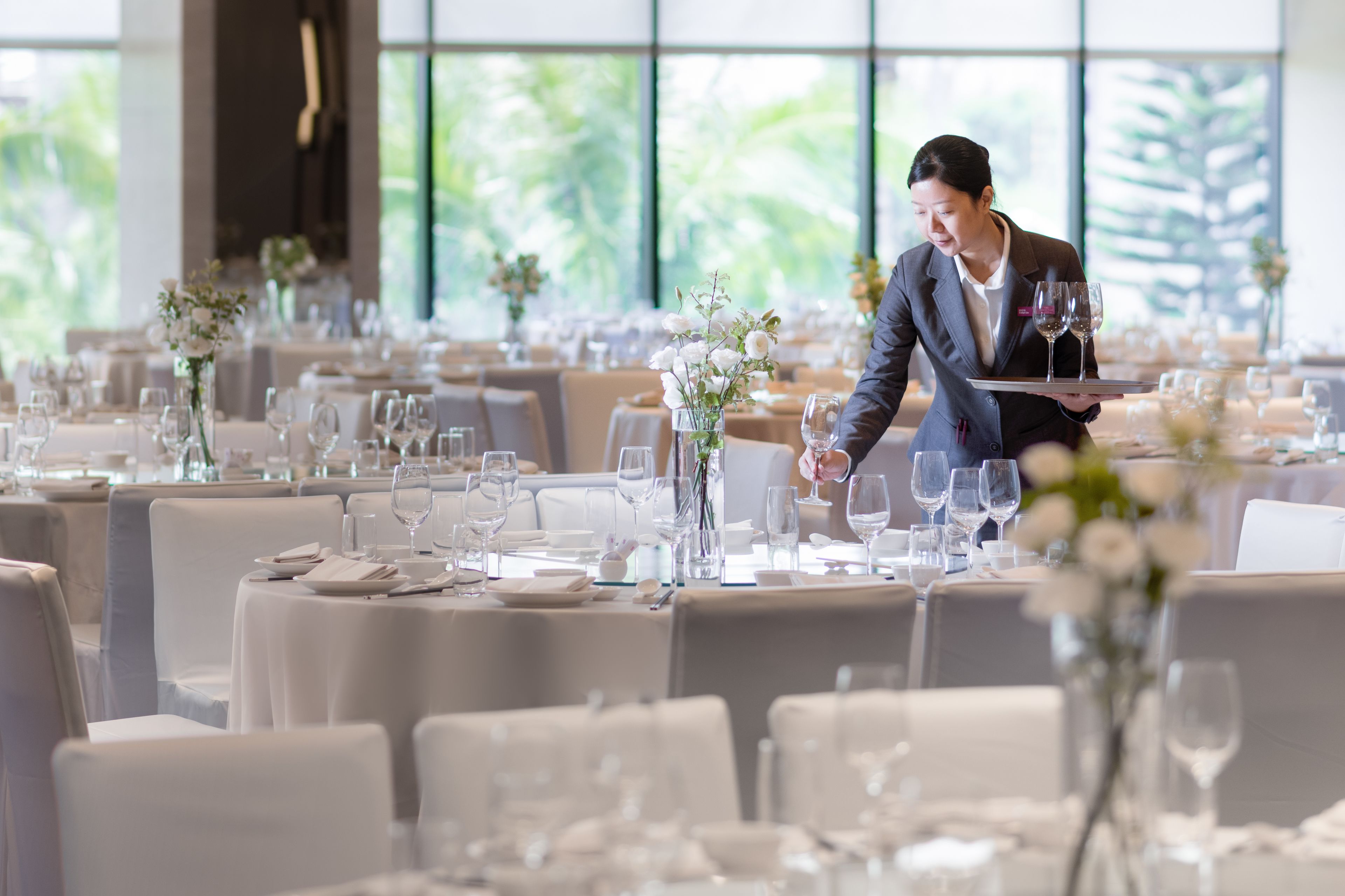A well-set dining area with tables arranged for guests, each with white tablecloths, wine glasses, and floral centerpieces.