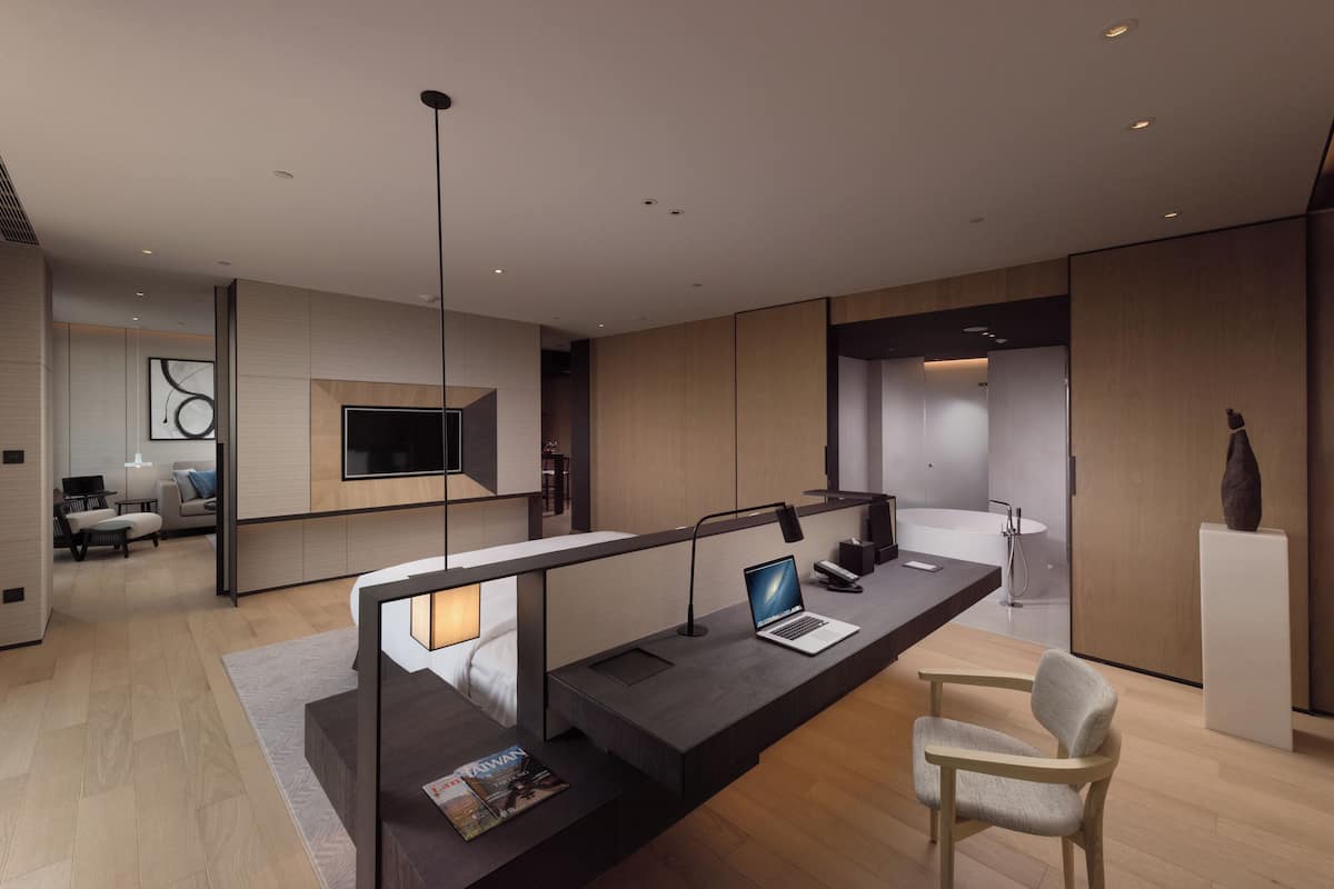 A modern hotel lobby with a sleek reception desk, a flat-screen TV, and a minimalist design.