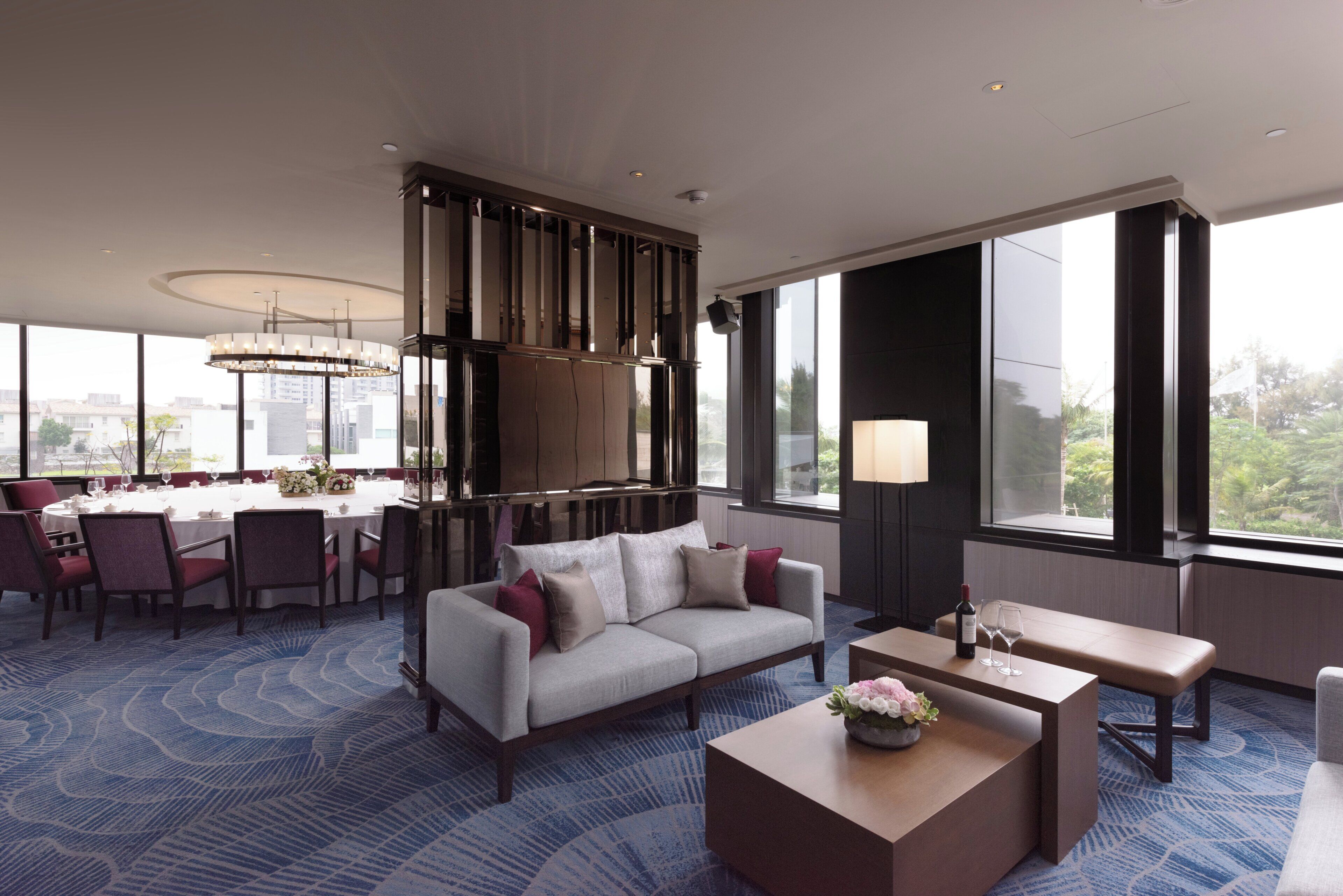 A modern hotel room with a dining area, a sofa, and a coffee table.