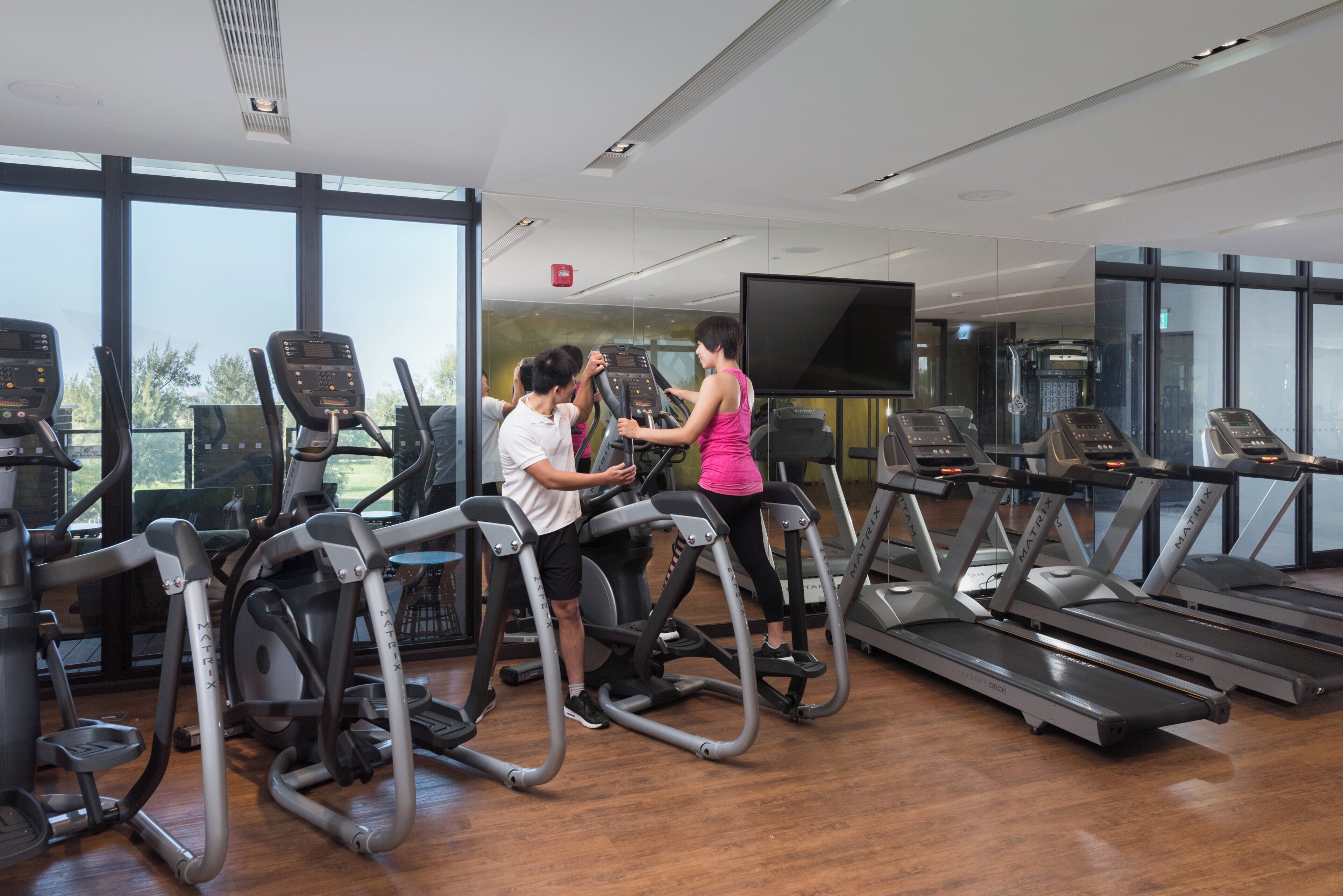 Un gimnasio con cintas de correr, bicicletas estáticas y otros equipos de cardio.