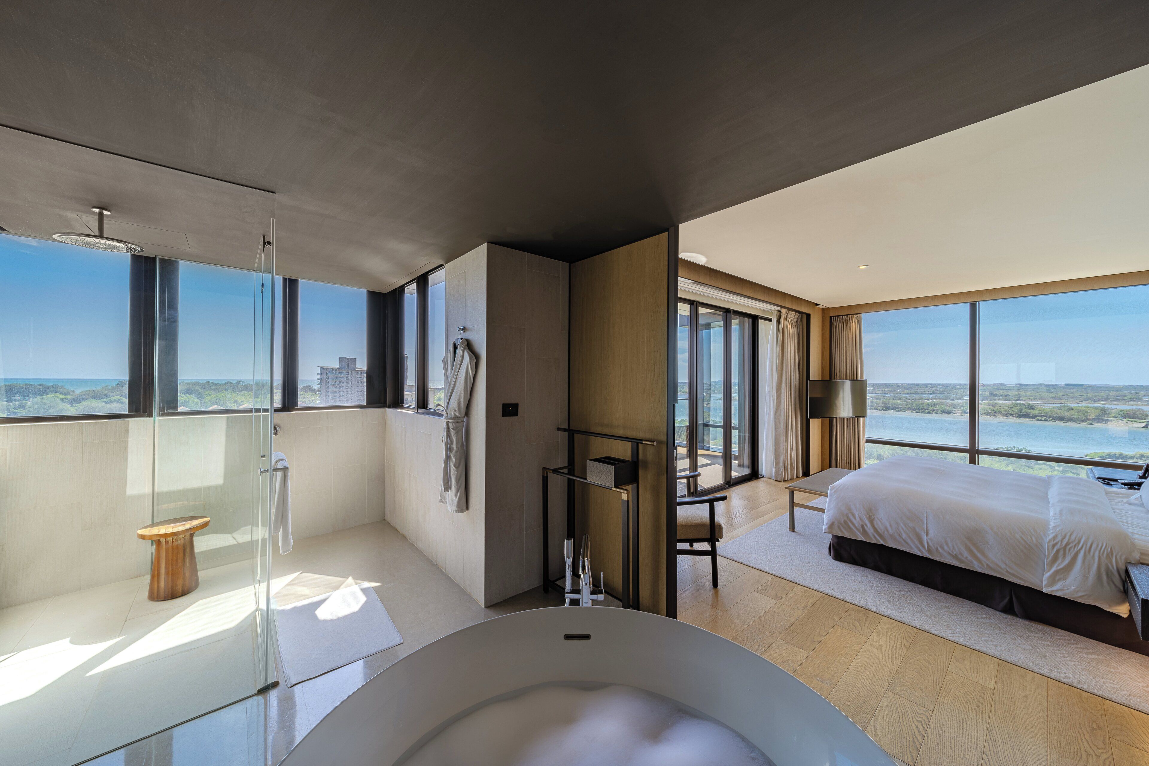 A modern hotel room with a large bed, a bathtub, and a view of the city.