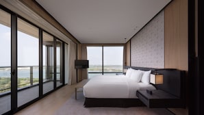 Habitación de hotel moderna con una cama grande, una mesita de noche, un televisor y vistas a la ciudad.