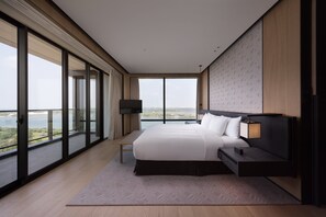 A modern hotel room with a large bed, a bedside table, a TV, and a view of the city. - Crowne Plaza Tainan by IHG (Tainan)
