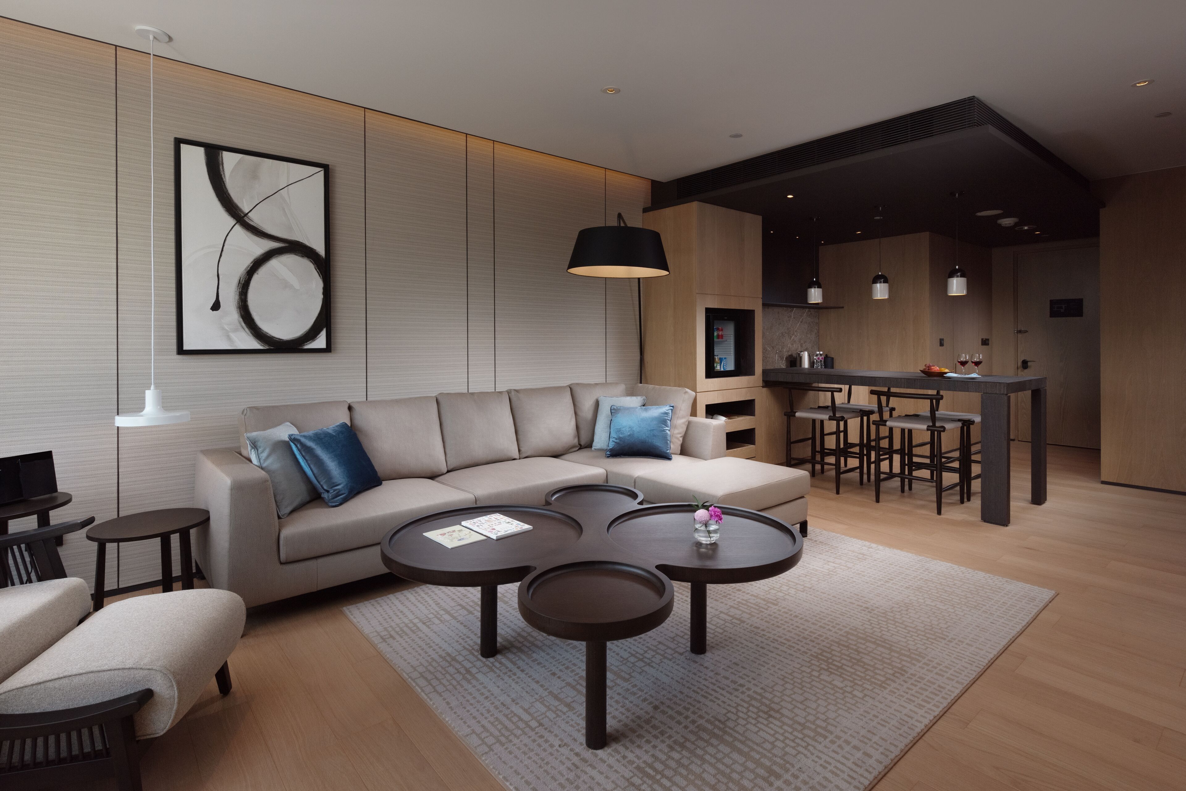 Un salon moderne avec un canapé, une table basse et un coin repas équipé de tabourets de bar.