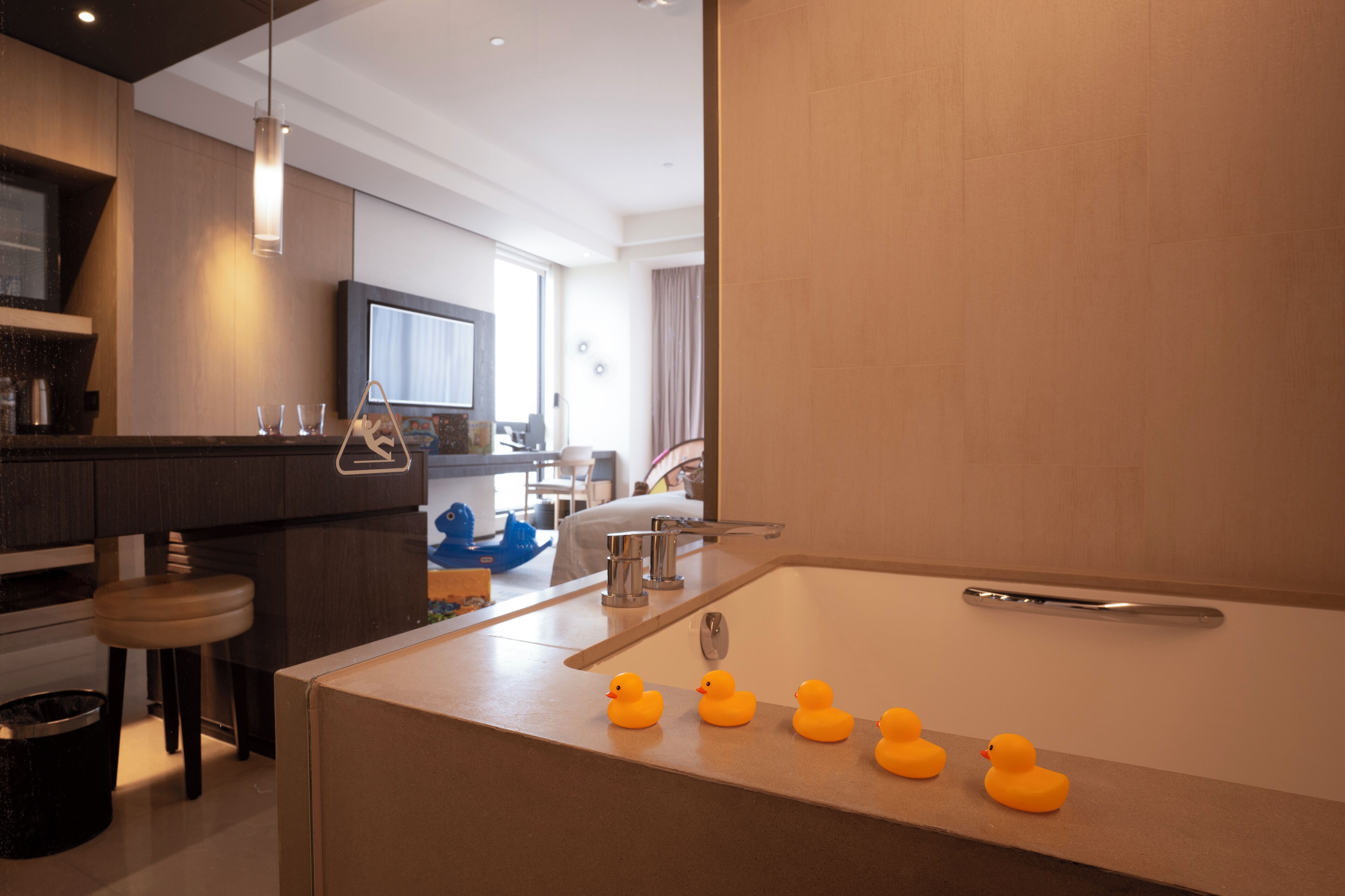 A modern kitchen with a central island, a sink, and a bar area. There are rubber ducks on the island.