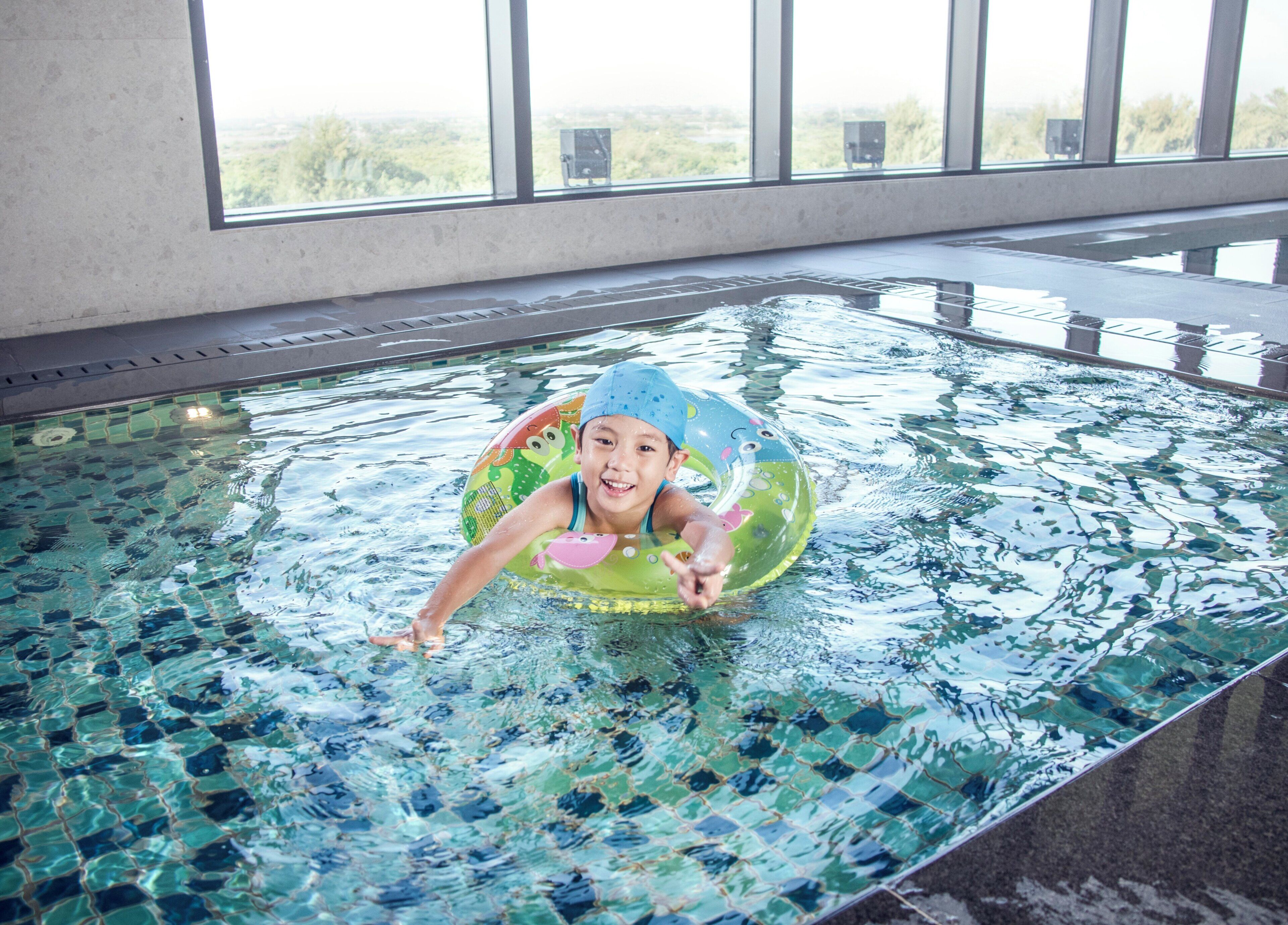 A pool with a child in a floatation ring.