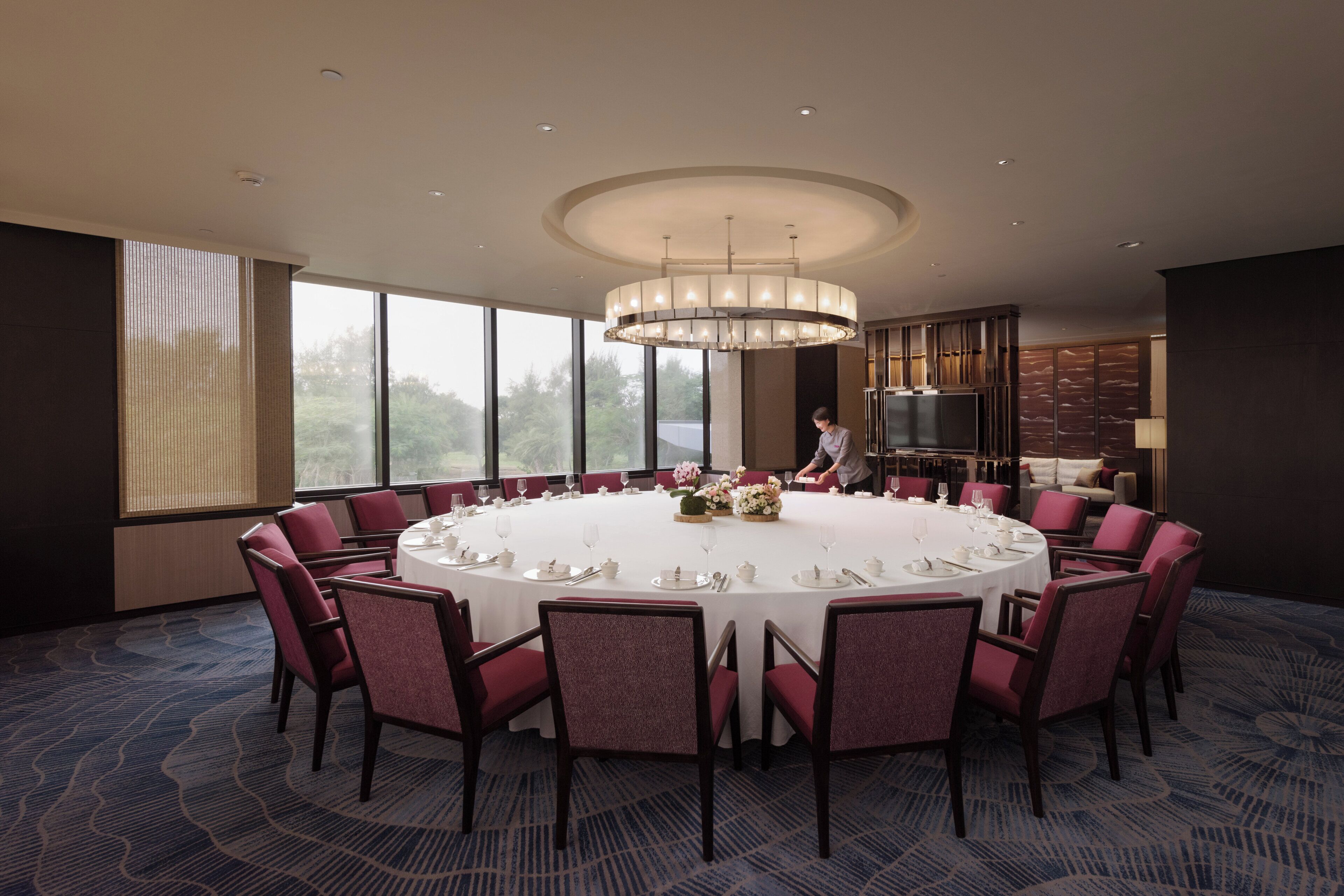 A conference room with a round table, chairs, and a chandelier.