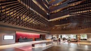 A spacious lobby with a modern design, featuring a reception desk, seating area, and a staircase.