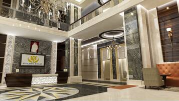 Een hotellobby met een receptiebalie, een kroonluchter, een bank en een groot rond vloerontwerp.
