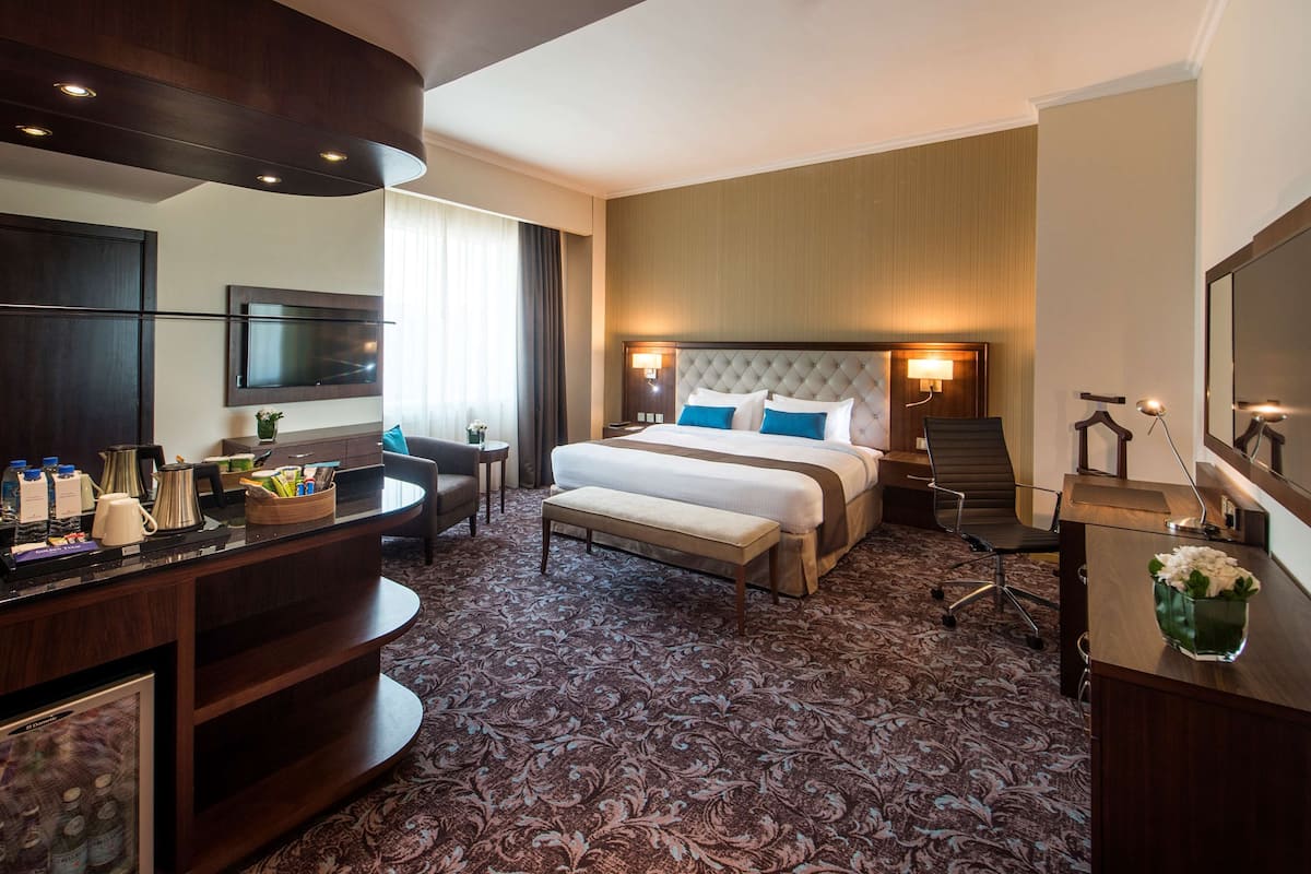 Une chambre d’hôtel avec un grand lit, un bureau, une télévision et un minibar.