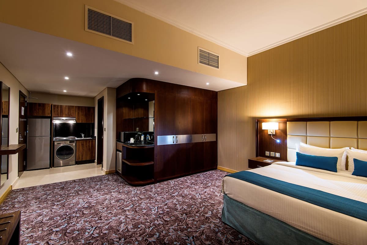 Une chambre d’hôtel avec un grand lit, un bureau intégré, une kitchenette et une salle de bain.