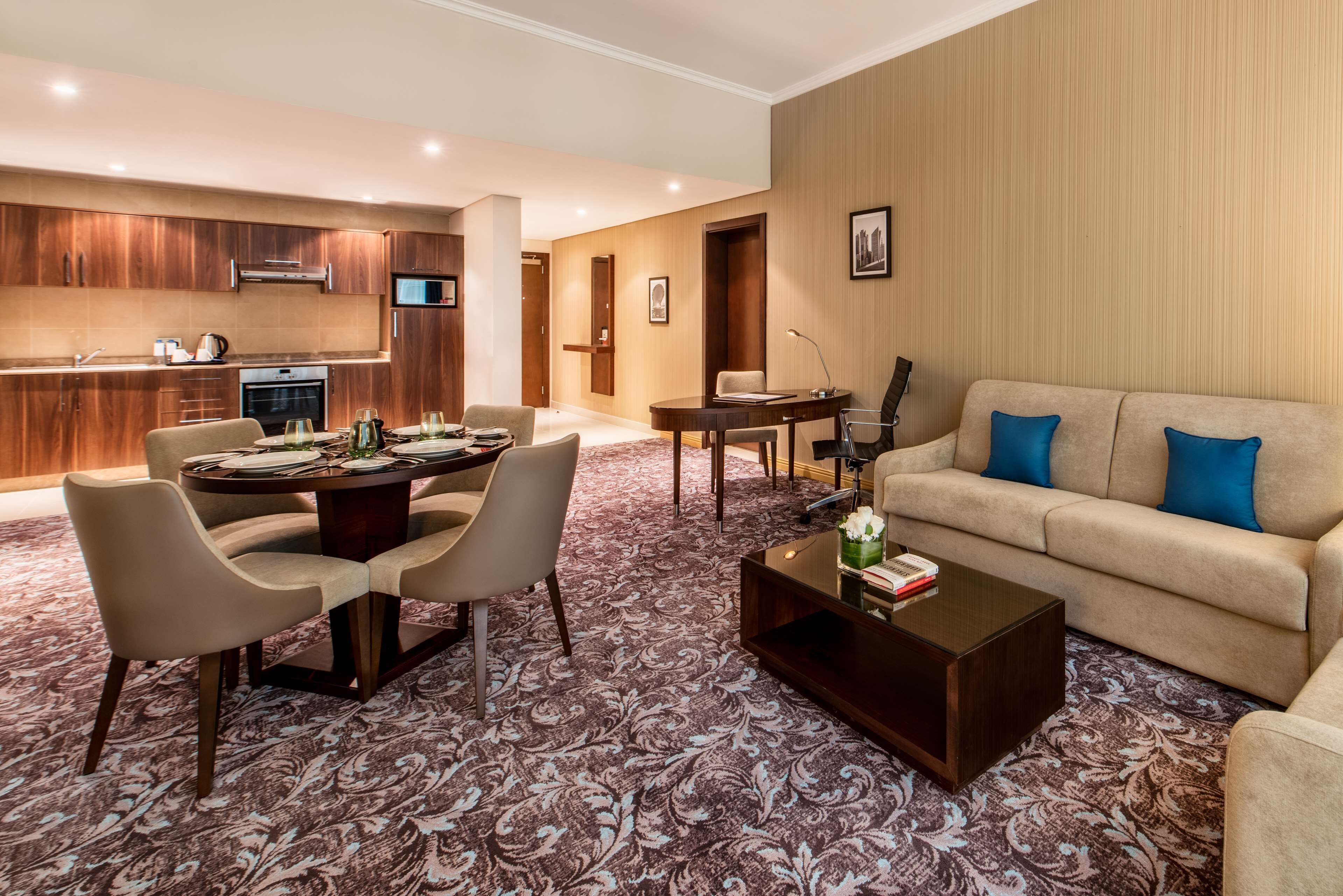 A modern hotel room with a dining area, a sofa, and a coffee table.