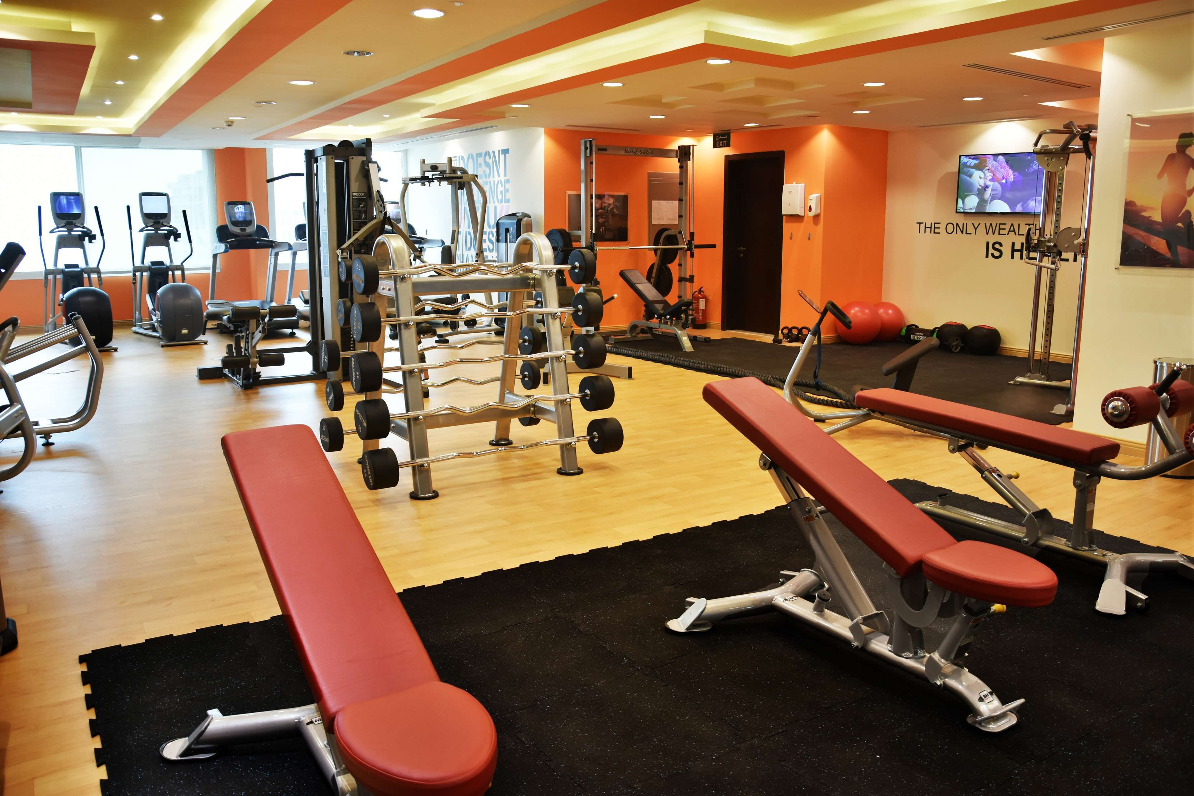 A gym with various exercise equipment, including treadmills, weight machines, and benches.
