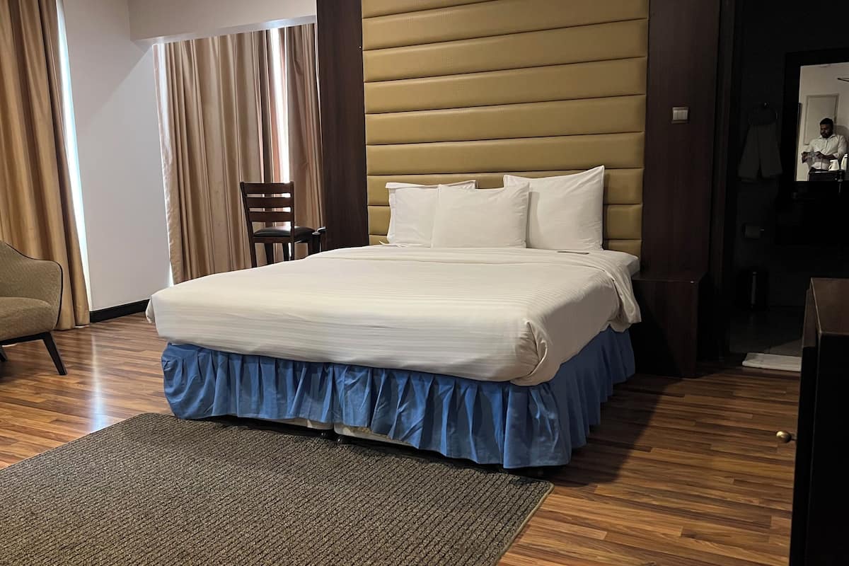 Ein Hotelzimmer mit Bett, Stuhl, Schreibtisch und Spiegel.