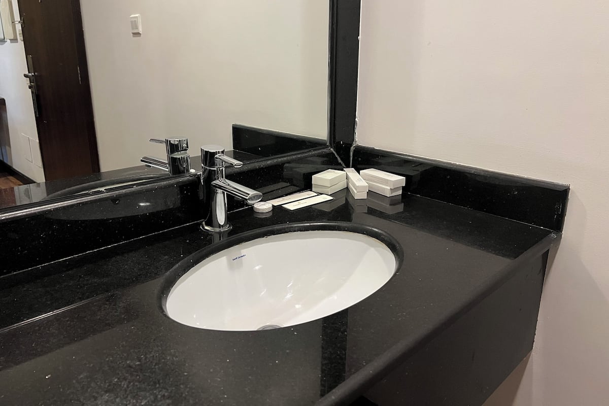 Eine schwarze Arbeitsplatte mit einem weißen Waschbecken und einem Spiegel.
