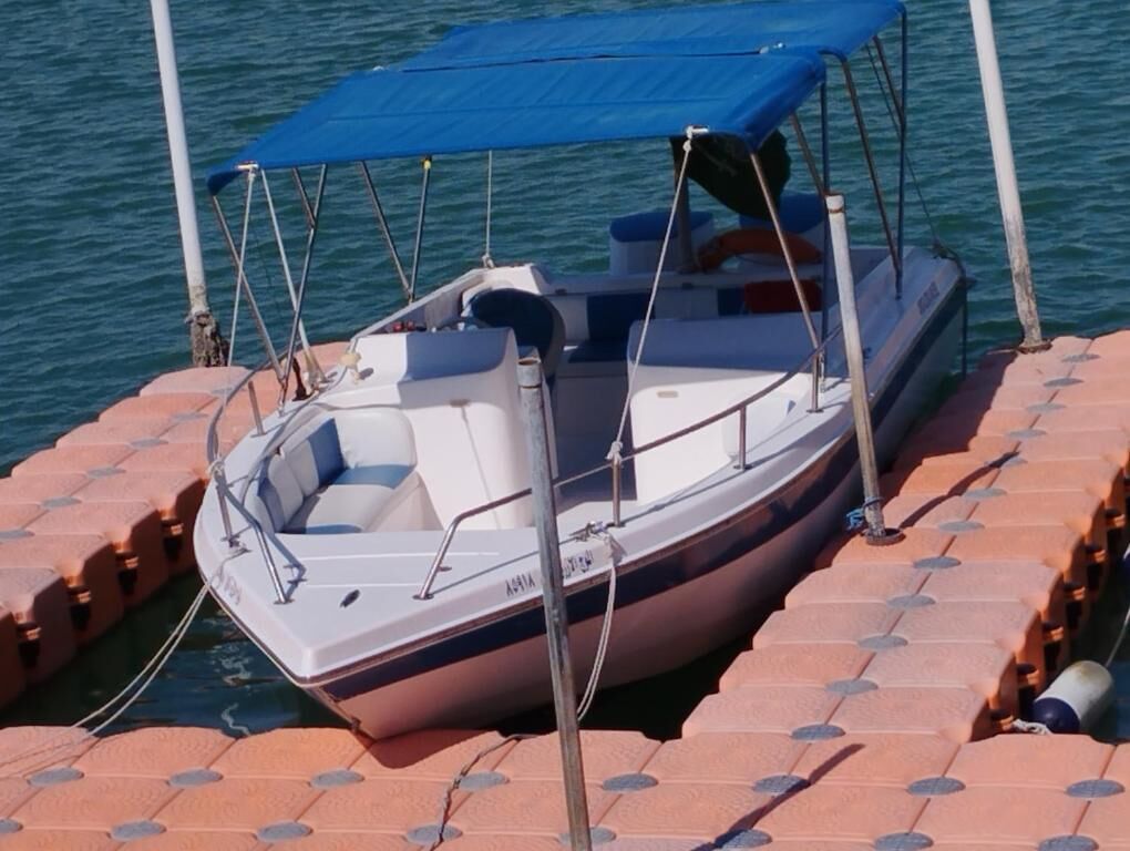A small boat docked on a floating platform with a blue canopy.