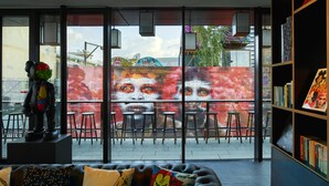 A modern interior with a sofa, bar stools, and a bookshelf. - citizenM London Shoreditch (London)