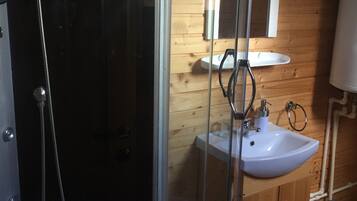 Un baño con cabina de ducha de vidrio, un lavamanos y paredes de madera.