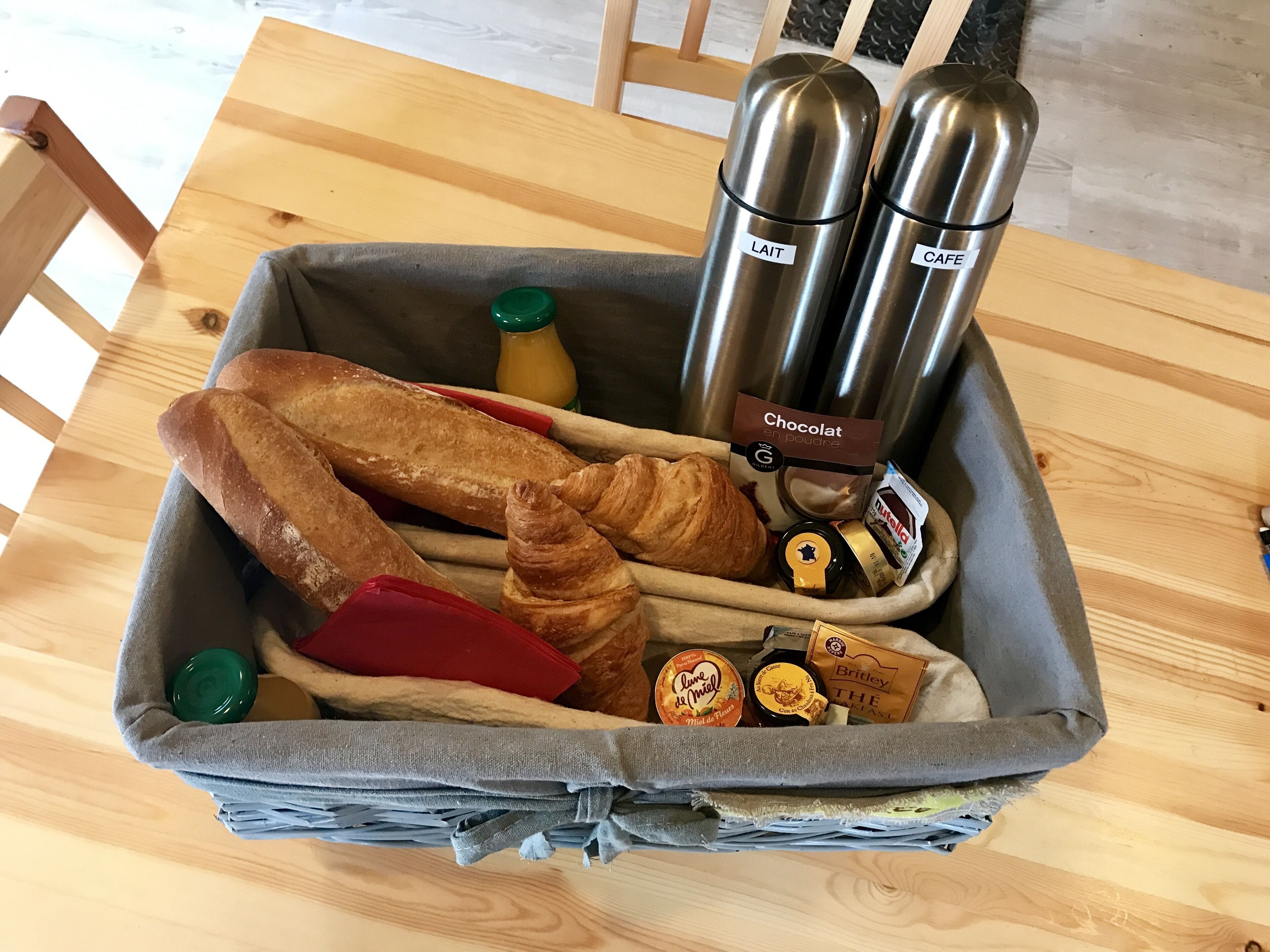 A basket containing bread, croissants, and chocolate spreads.