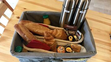 A basket containing bread, croissants, and chocolate spreads.
