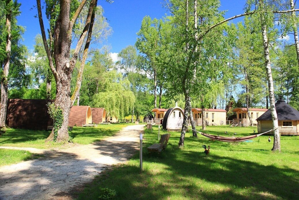 A campsite with wooden cabins, a hammock, and a dirt path.