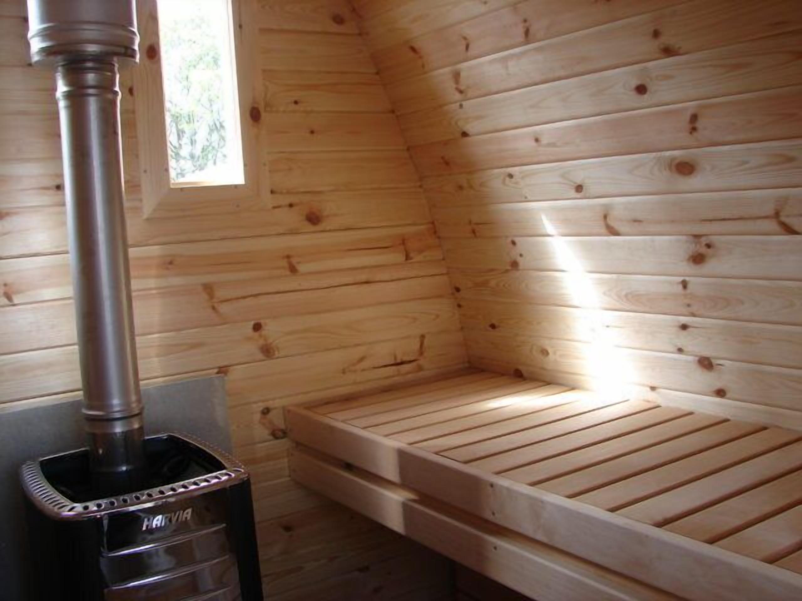 A wooden sauna with a bench and a steam generator.
