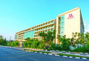 A multi-story hotel with a modern design, featuring a prominent logo on the facade.