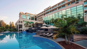 Un hotel con piscina, sillones de descanso y palmeras.