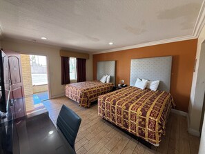 A hotel room with two beds, a desk, and a chair.